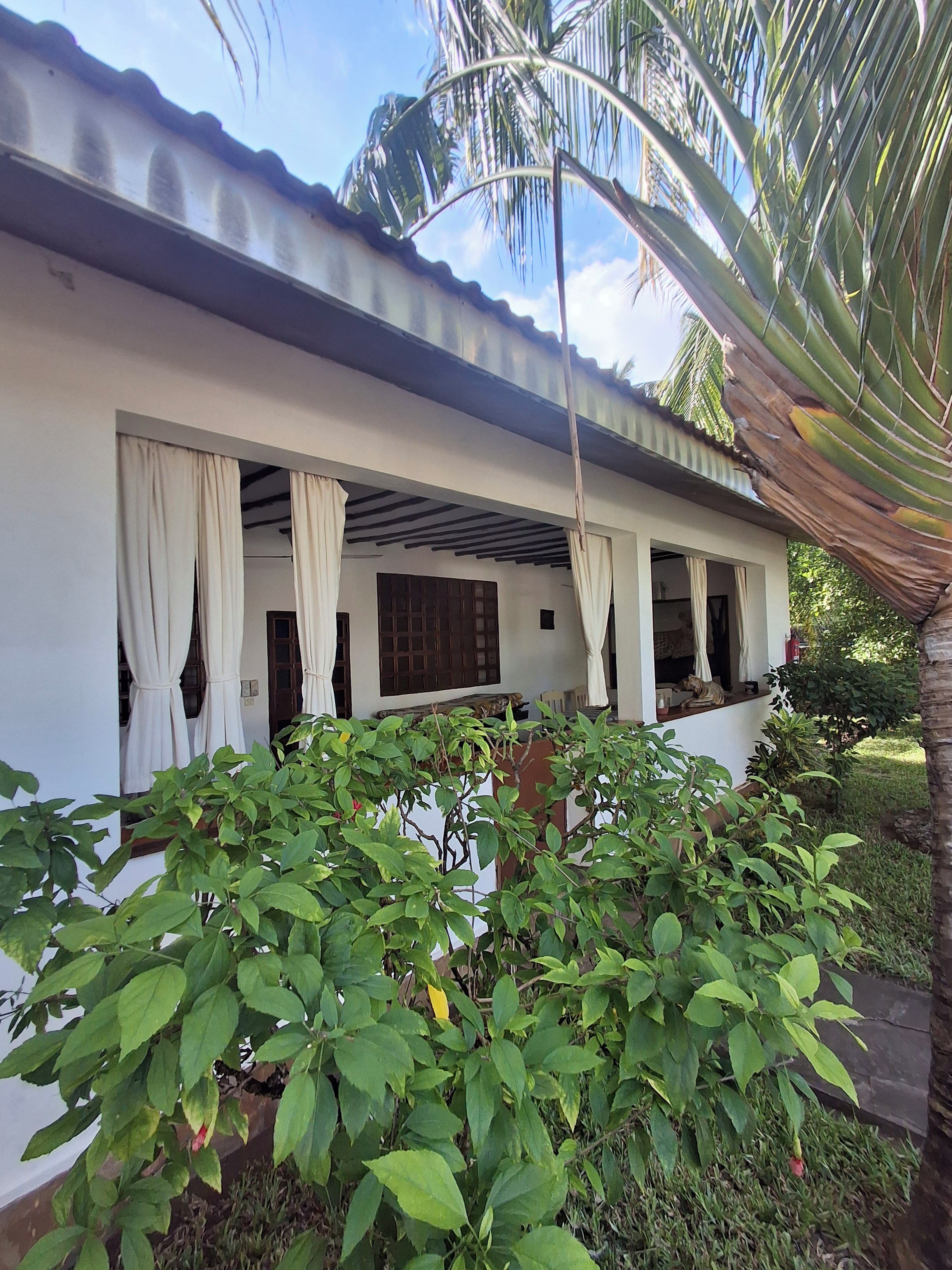 A building with a covered porch, white walls, and a tiled roof.