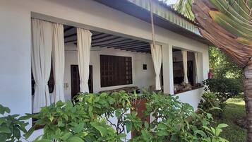 A building with a covered porch, white walls, and a tiled roof.