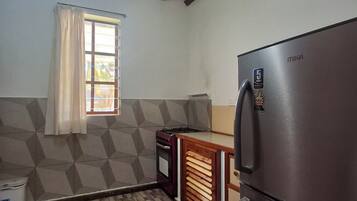 A kitchen with a built-in stove, a refrigerator, and a window with curtains.