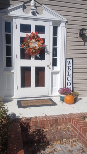 A white house with a welcome sign, a doormat, a large pumpkin, and a brick step leading to the door. - 3 Miles to Furniture Market • 8 Beds • Fast Wi‑Fi • Lake Views (High Point)