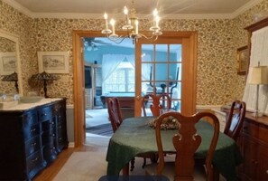 A dining room with a chandelier, wooden chairs, a table with a green tablecloth, and a view through a doorway to another room. - 3 Miles to Furniture Market • 8 Beds • Fast Wi‑Fi • Lake Views (High Point)