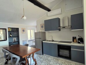 A modern kitchen with grey cabinets, a built-in oven, and a dining area with a wooden table and chairs. - BluOltremare Nervi - Historical Seaview Residence (Genova)