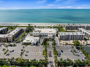 A hotel with a parking lot, multiple buildings, and a beach view. - Sundial F203 Sanibel Beach Condo Steps to Beach (Sanibel)