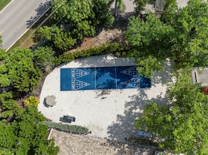 A blue shuffleboard court surrounded by trees and a paved area. - Sundial F203 Sanibel Beach Condo Steps to Beach (Sanibel)