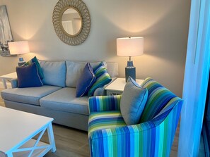 A living room with a sofa, armchair, two side tables, and a lamp. - Sundial F203 Sanibel Beach Condo Steps to Beach (Sanibel)