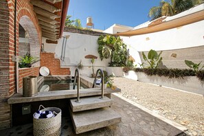A private outdoor bathroom with a sink, two faucets, and a small step leading to a shower area. There are potted plants and a water tank in the background. - ⭐ Charming Bucerías Hacienda | Private Pool & Courtyard (Bucerías)