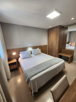 A modern hotel room with a large bed, a bedside table with a lamp, a wooden wardrobe, and a bench. - Cozy 1-bedroom apartment in fantastic Rio de Janeiro with AC and gym (Rio de Janeiro)