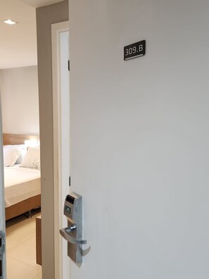 Een hotelkamerdeur met een digitaal slot en een bordje met het kamernummer 309.B.