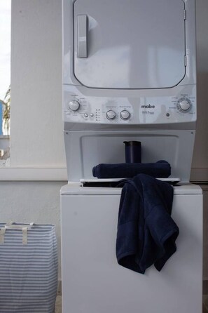 A front-loading washing machine with a control panel and a blue towel hanging on the door. - Boutique Bucerías Hacienda | Spacious Private Terrace (Bucerías)