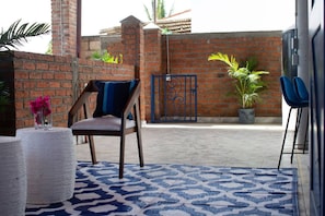 A patio area with a chair, a patterned rug, a potted plant, and a metal gate. - Boutique Bucerías Hacienda | Spacious Private Terrace (Bucerías)