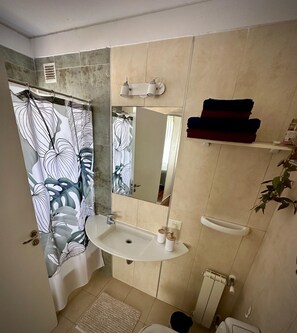 A bathroom with a shower curtain, sink, mirror, and towel rack. - Confortable 3 Ambientes en Núñez, zona Segura, conectado y con Balcón (Buenos Aires)