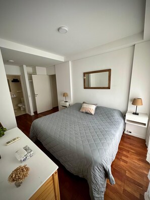 A bedroom with a large bed, bedside tables, a mirror, and a wardrobe. - Confortable 3 Ambientes en Núñez, zona Segura, conectado y con Balcón (Buenos Aires)