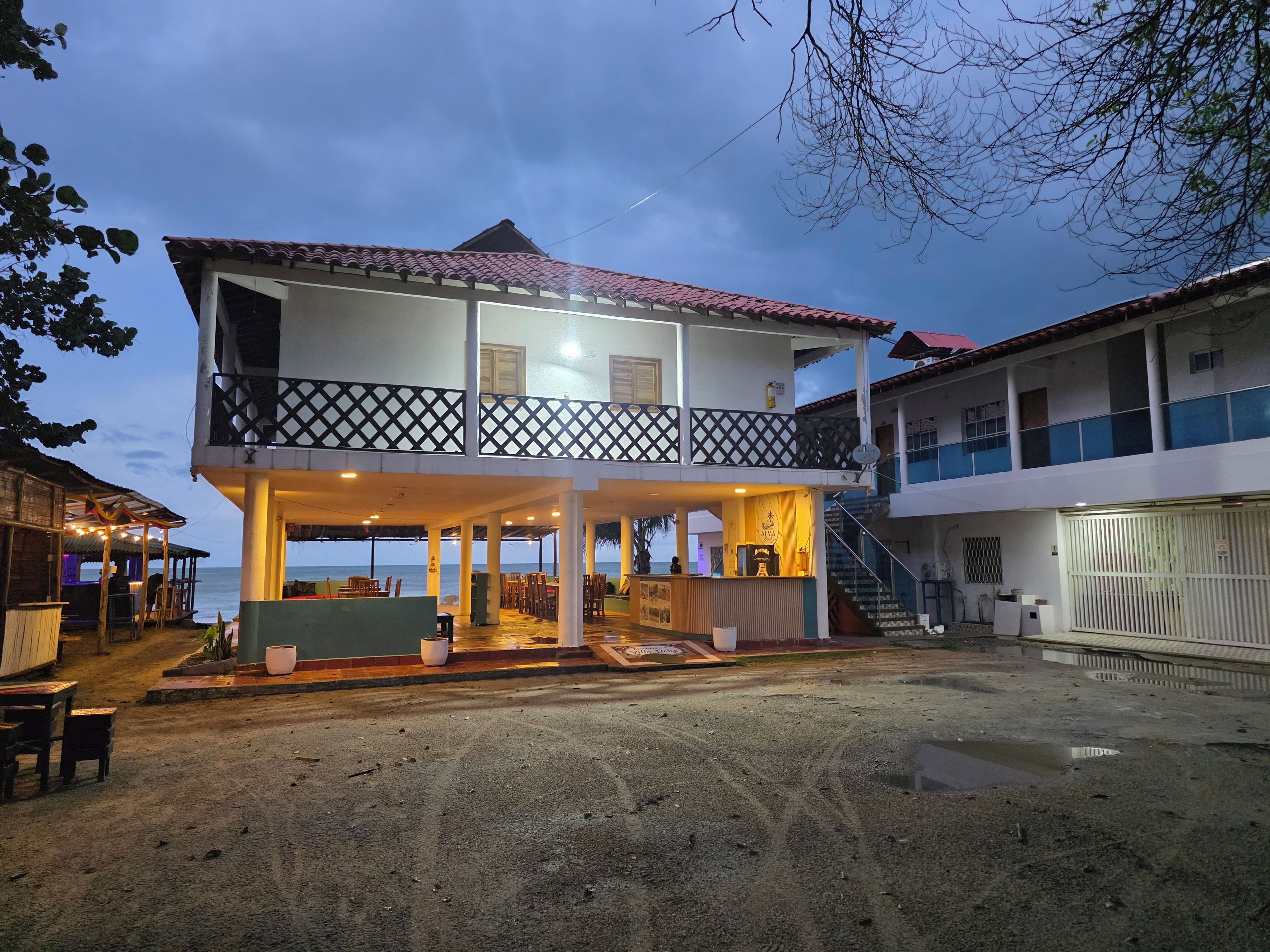 Um edifício de dois andares com varanda, área de estar coberta e vista para o mar.