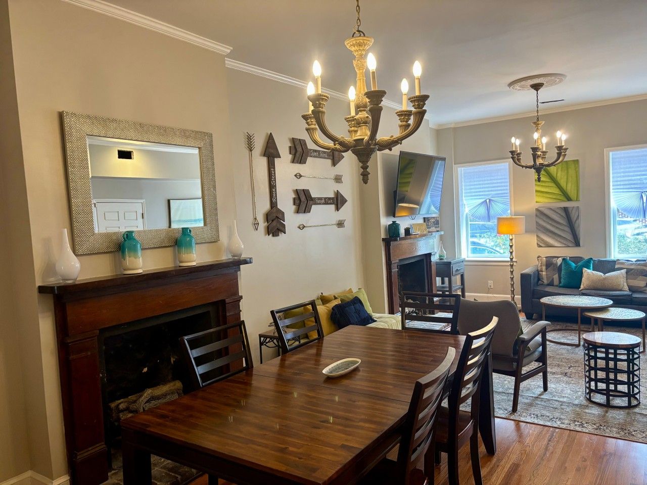 A dining area with a wooden table and chairs, a fireplace, and a chandelier.