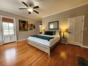 A bedroom with a bed, a ceiling fan, a door, and a window. - Park Place Estate – Ideal for Groups, 3 Units & Courtyard, 3‑Min Walk to Forsyth (Savannah)
