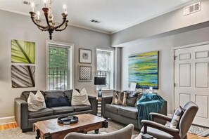 A living room with a sofa, armchair, coffee table, and artwork on the walls. - Park Place Estate – Ideal for Groups, 3 Units & Courtyard, 3‑Min Walk to Forsyth (Savannah)