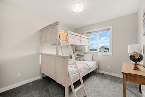 A bunk bed room with a window, a lamp, and a globe on a table. - Family Getaway | Glacier Ridge | Calgary NW (Calgary)