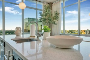 A modern kitchen with a large window, a sink, a bowl, and a potted plant. - Downtown/FreeParking/Rooftop Pool/ King Plush Beds (Atlanta)