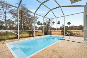 A covered swimming pool with a view of trees and a clear sky. - Afterglow Manatees:Pool /Golf/Near Spring/Spacious (Crystal River)