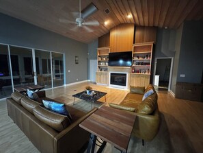 A modern living room with a fireplace, leather sofas, a coffee table, and a flat-screen TV. - Afterglow Manatees:Pool /Golf/Near Spring/Spacious (Crystal River)