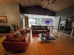 A spacious living room with a brown leather sofa, a coffee table, and a kitchen area in the background. - Afterglow Manatees:Pool /Golf/Near Spring/Spacious (Crystal River)