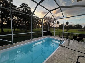 Ein überdachter Pool mit Blick auf eine Rasenfläche und Bäume.
