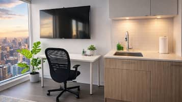 A modern kitchen with a flat-screen TV, a sink, and a window overlooking a cityscape.