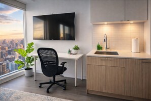 A modern kitchen with a flat-screen TV, a sink, and a window overlooking a cityscape. - The Boutique Suites - Jarvis Street (Toronto)