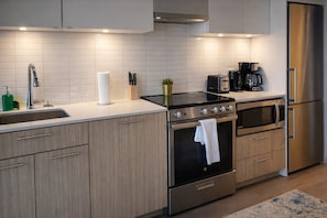 A modern kitchen with a stainless steel refrigerator, double ovens, a coffee maker, and a sink. - The Boutique Suites - Jarvis Street (Toronto)