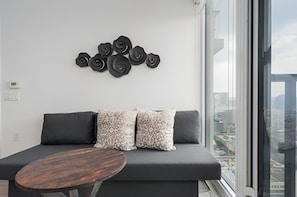 A modern living room with a gray sofa, patterned pillows, a wooden coffee table, and a wall-mounted abstract art piece. - The Boutique Suites - Jarvis Street (Toronto)