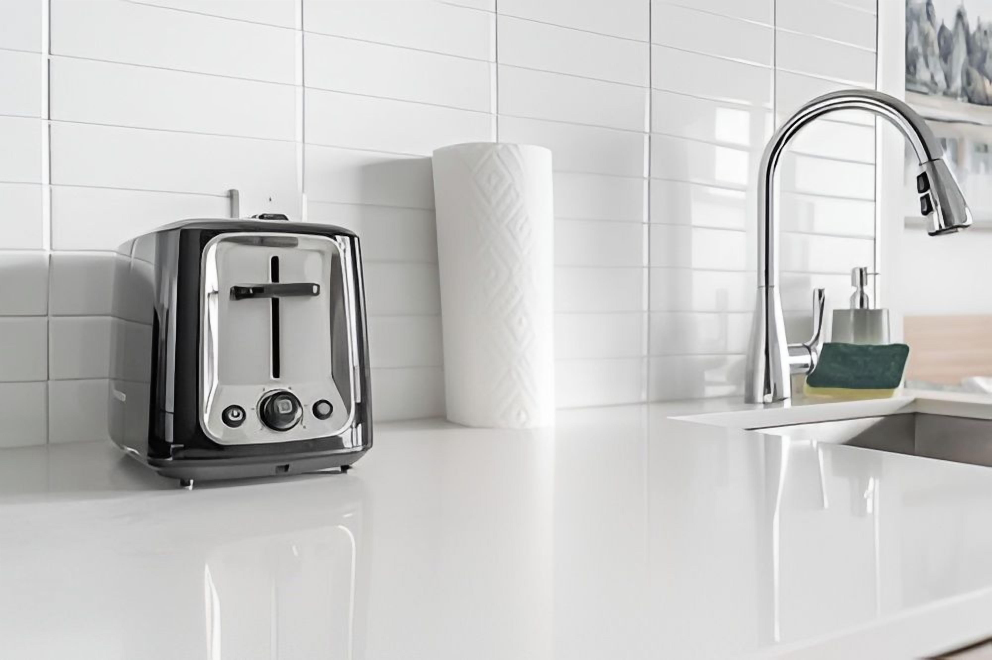 Une cuisine moderne équipée d’un grille-pain en acier inoxydable, d’un rouleau d’essuie-tout et d’un évier avec un robinet.