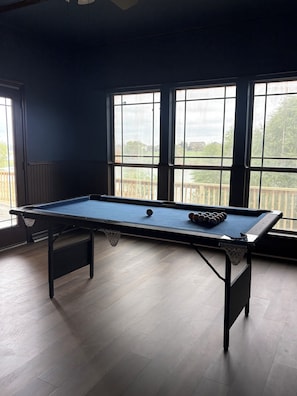 A pool table with a blue felt surface, a white cue ball, and a set of pool cues. - LAKE view 4-bedroom HOmE with GAME Room (San Antonio)