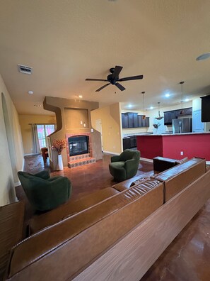 A living room with a fireplace, green armchairs, and a wooden bench. - LAKE view 4-bedroom HOmE with GAME Room (San Antonio)