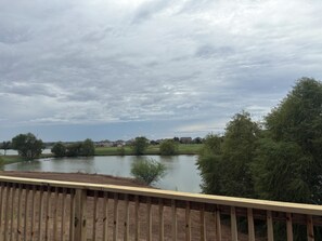 A wooden deck overlooking a lake with houses in the background. - LAKE view 4-bedroom HOmE with GAME Room (San Antonio)
