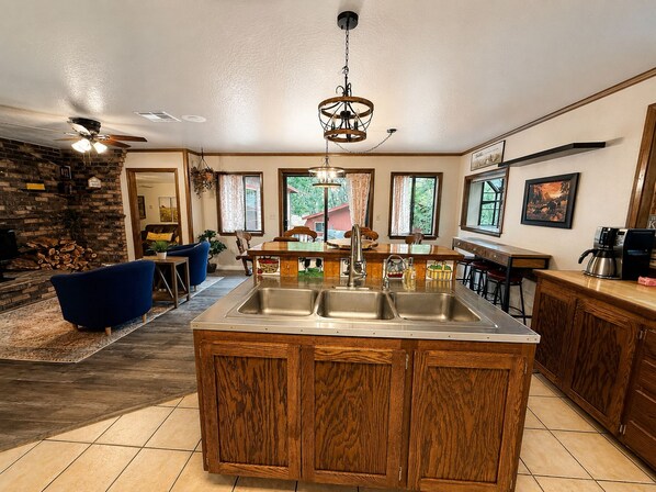 A kitchen with a central island, wooden cabinets, and a bar area.
