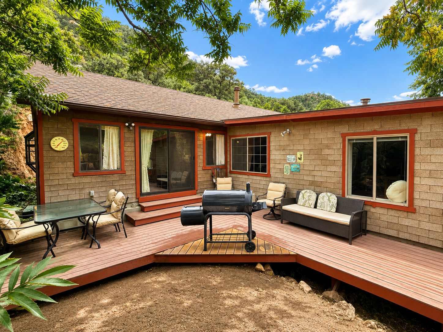 Une maison dotée d’une terrasse, de mobilier d’extérieur et d’un barbecue.
