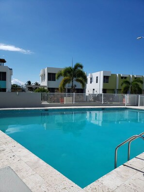 A swimming pool with a clear blue water surface, surrounded by a white fence, and adjacent to a building with a modern architectural style. - * * CASA PALMA * *  Beachside Tropical Oasis (Ensenada)
