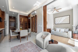 A modern living room with a sofa, armchair, dining table, and a ceiling fan. - Penthouse 1BR | Rooftop Pool, Hot Tub & Romantic Zone (Puerto Vallarta)
