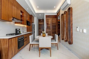 Een moderne keuken met houten kasten, een eethoek met een witte tafel en stoelen, en een wand met een patroon.