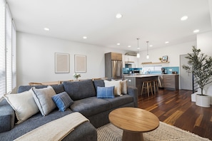 A modern living room with a grey sofa, wooden coffee table, and a kitchen in the background. - Rooftop Retreat w/ Stunning Views Ballard Gem (Seattle)