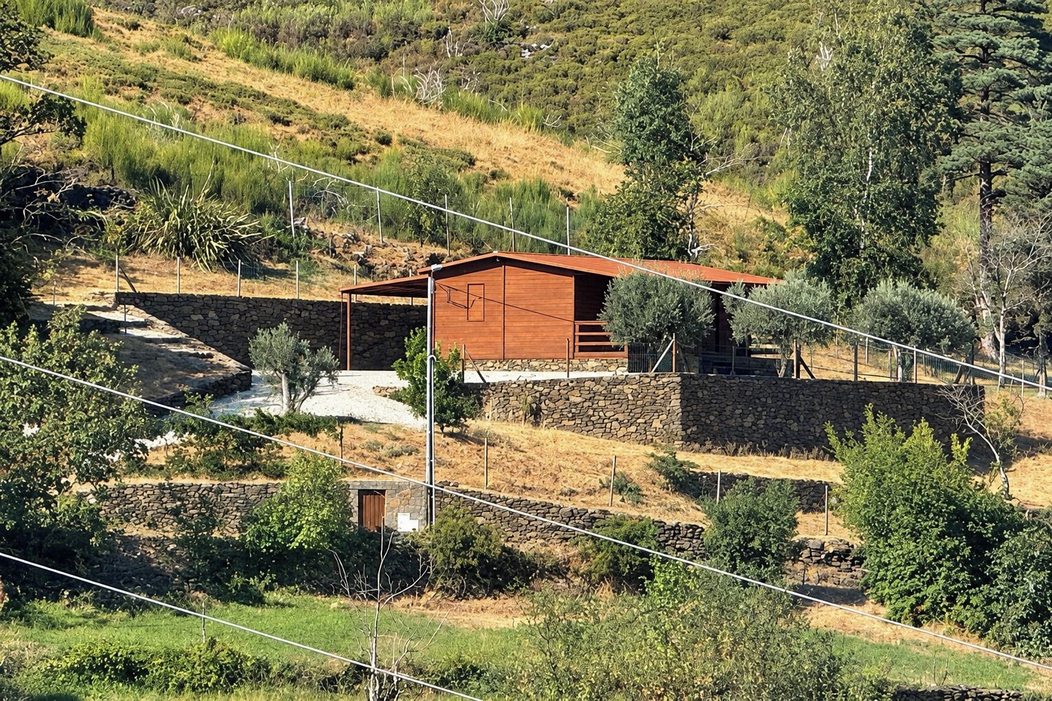 Eine rustikale Holzhütte mit Stein Fundament, umgeben von einer kargen, hügeligen Landschaft mit spärlicher Vegetation.