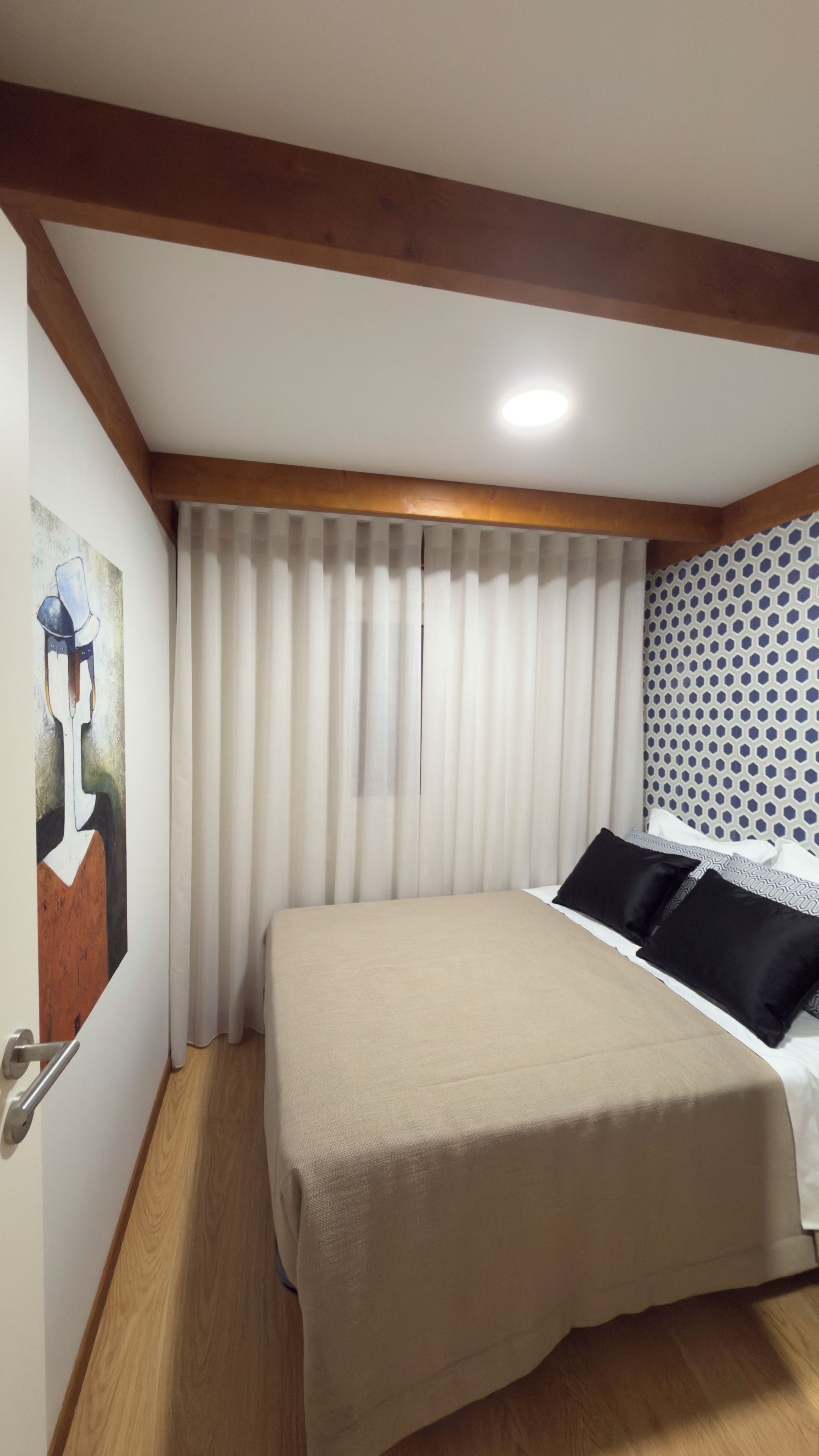 Un dormitorio con cama, un cuadro en la pared y una ventana con persianas.