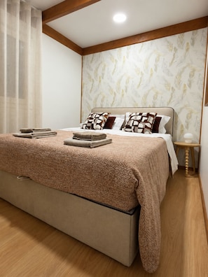 A bedroom with a bed, pillows, a bedside table, and a lamp.