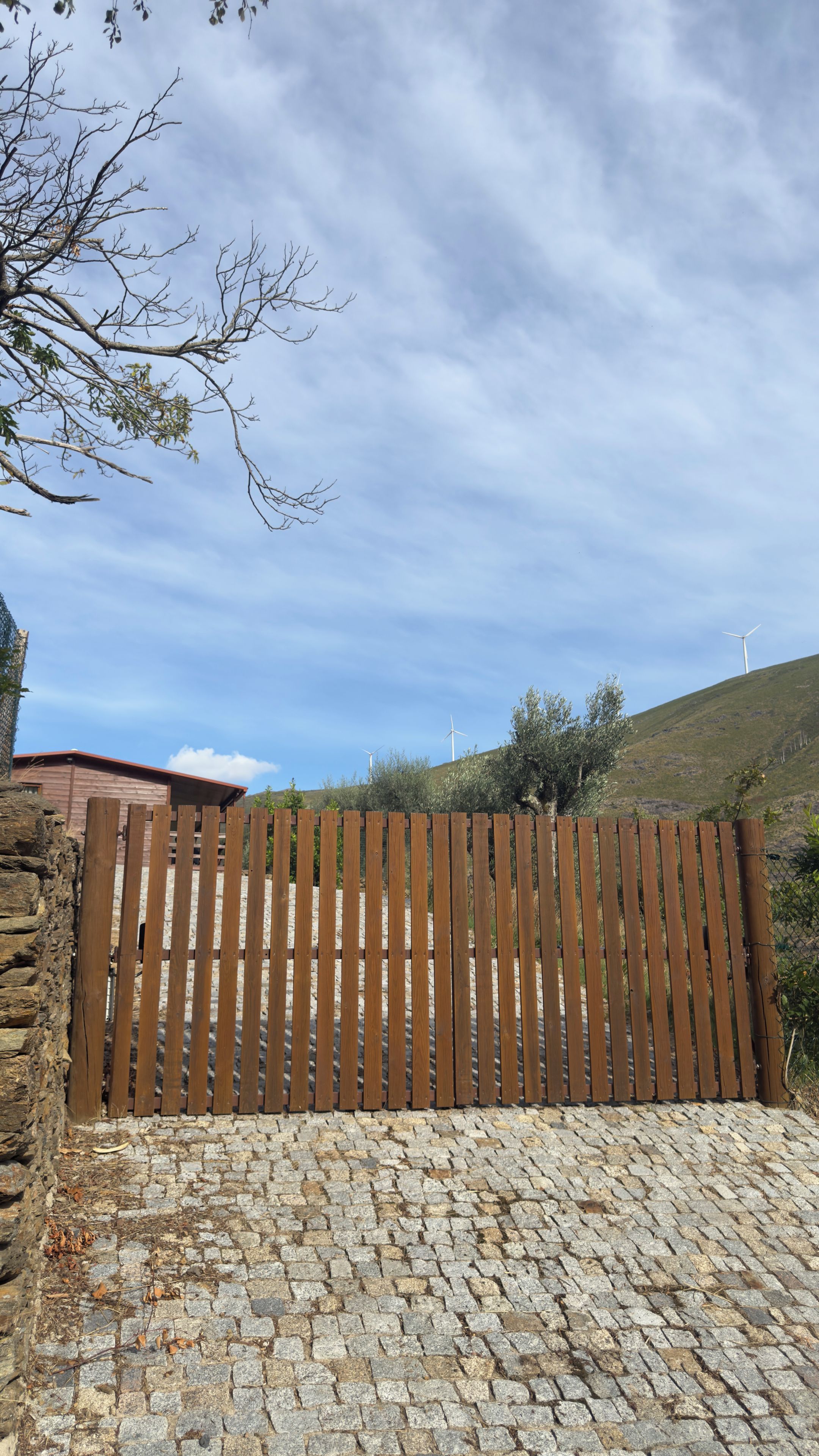 A wooden fence with a stone wall and cobblestone ground.