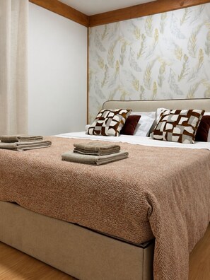 A neatly made bed with a patterned bedspread, pillows, and folded towels.