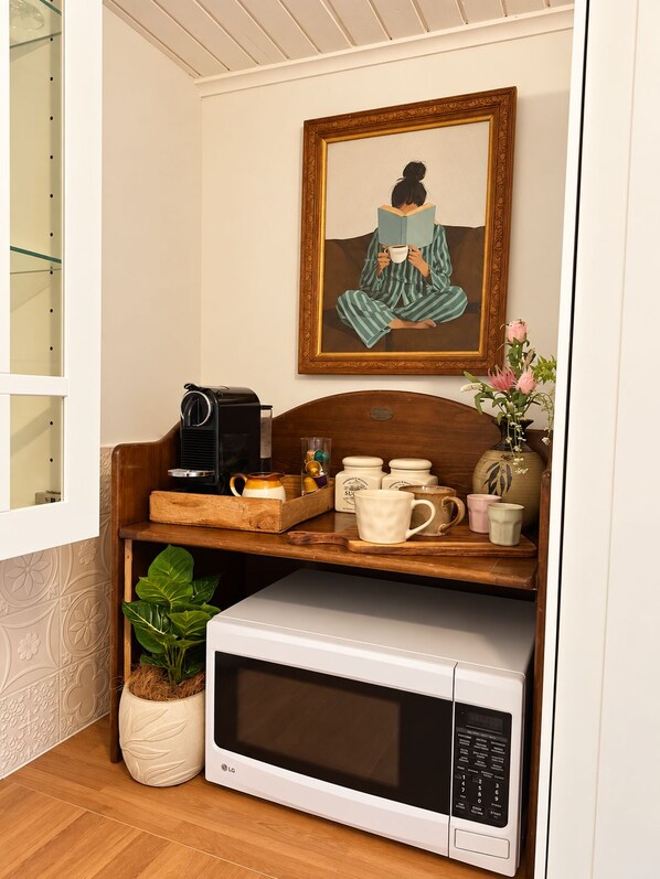 A kitchen area with a microwave, a coffee maker, and a shelf with mugs and a plant. - Entire 3BR Beachside House in the Heart of St Kilda (St Kilda)