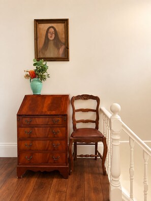 A wooden dresser with drawers, a chair, a vase with flowers, and a framed picture on the wall. - Entire 3BR Beachside House in the Heart of St Kilda (St Kilda)