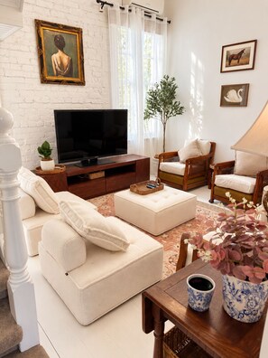 A living room with a sofa, chairs, a TV, and a plant. - Entire 3BR Beachside House in the Heart of St Kilda (St Kilda)