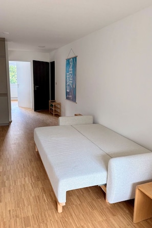 A room with a bed, a wooden floor, a door, and a poster on the wall. - Waldhaus A1/4 (CharmingStay), (Flumserberg Tannenboden), by Interhome (Flumserberg Tannenheim)
