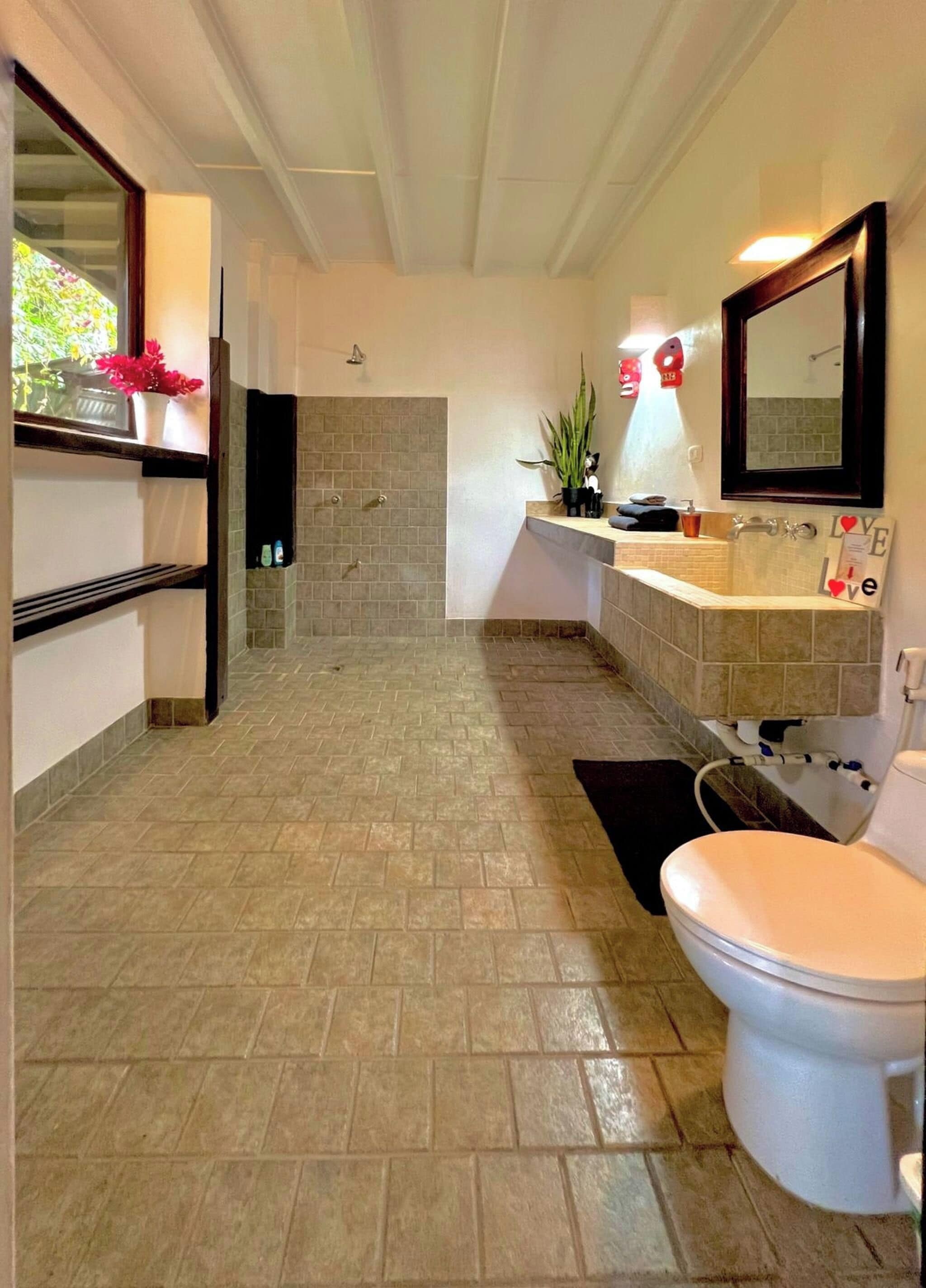 Un baño con ducha, inodoro, lavamanos y espejo.